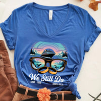 Blue custom tee with cruise ship, sunglasses, and rings graphic, 'We Still Do' text, mountains.