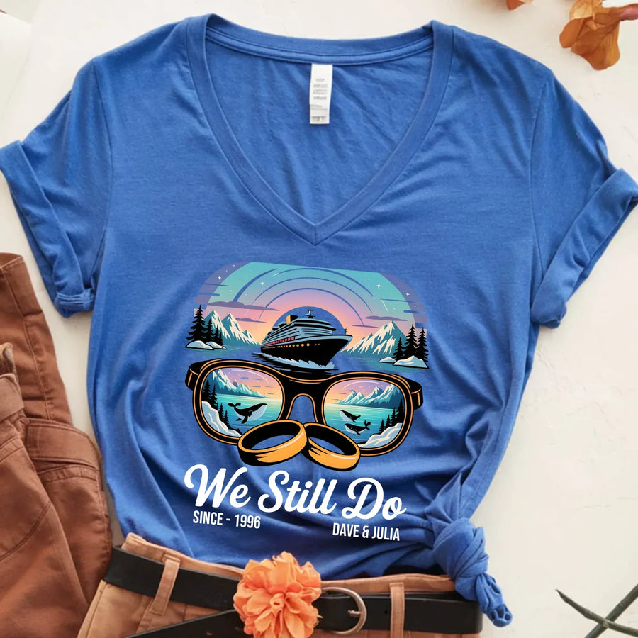 Blue custom tee with cruise ship, sunglasses, and rings graphic, 'We Still Do' text, mountains.