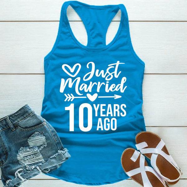Blue tank top with 'Just Married 10 Years Ago' text, paired with denim shorts and sandals on a wooden surface.