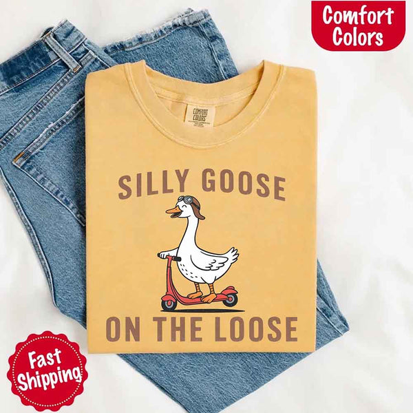 May include a mustard folded Comfort Colors t-shirt with the phrase 'Silly Goose On The Loose' — a playful and quirky design perfect as a funny gift shirt