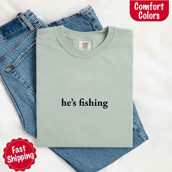 May include a folded bay Comfort Colors t-shirt with the phrase 'He’s Fishing' — a funny and laid-back design, ideal for women who enjoy a relaxed fit with humor