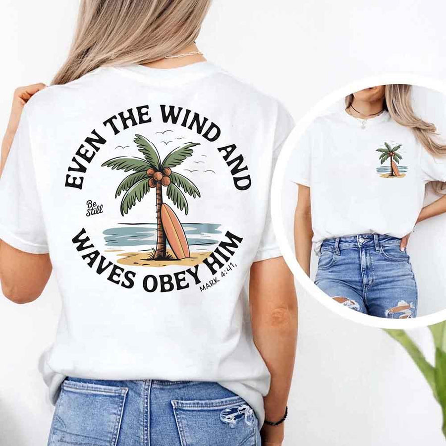 May include a woman wearing a white t-shirt with a small front graphic and a large back design of a palm tree and surfboard by the beach, surrounded by the words 'Even the Wind and Waves Obey Him – Mark 4:41' in a circular layout, inspired by a Christian Bible verse