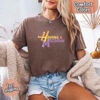 May include a woman wearing a espresso Comfort Colors T-shirt with the phrase “having a meltdown” in bold black text, styled for a humorous and relatable casual look.