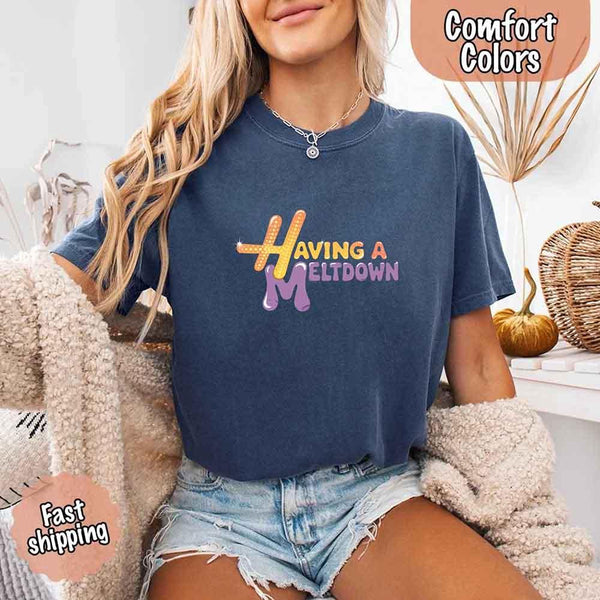 May include a woman wearing a blue jean Comfort Colors T-shirt with the phrase “having a meltdown” in bold black text, styled for a humorous and relatable casual look.