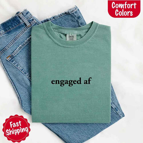 Green t-shirt with 'engaged af' text on a white background, surrounded by jeans. Comfort Colors logo visible.