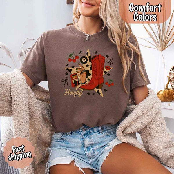 May include a woman wearing a espresso Comfort Colors T-shirt featuring the word “howdy” with a colorful star collage design, styled in a fun western or cowgirl-inspired look.