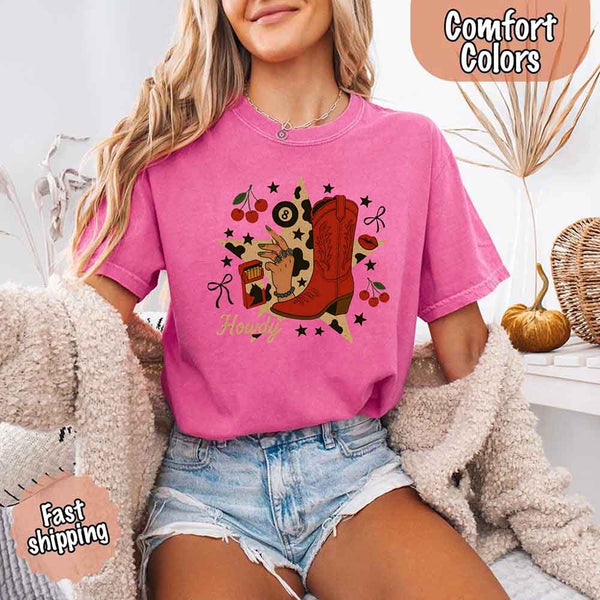 May include a woman wearing a crunchberry Comfort Colors T-shirt featuring the word “howdy” with a colorful star collage design, styled in a fun western or cowgirl-inspired look.