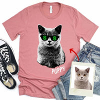 Pink t-shirt with a cat graphic and sunglasses, surrounded by jeans, sneakers, and a photo of a cat.