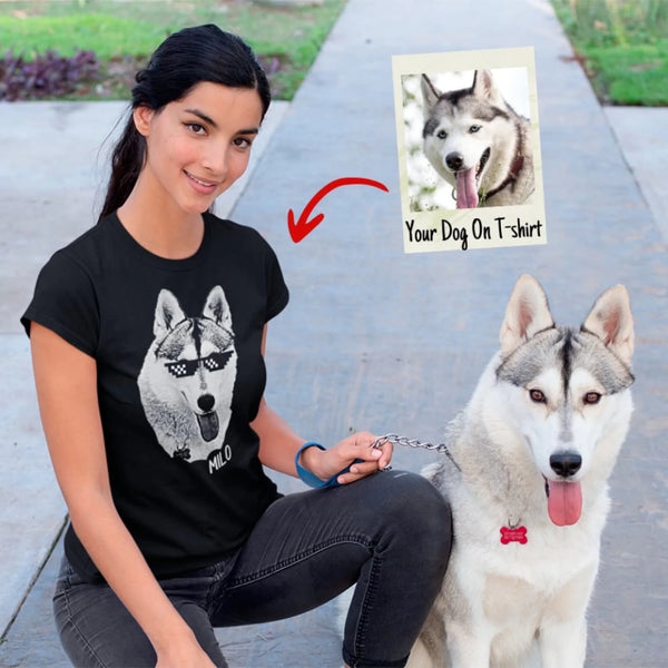 Woman wearing a black t-shirt with a dog graphic, sitting next to a real dog on a path.