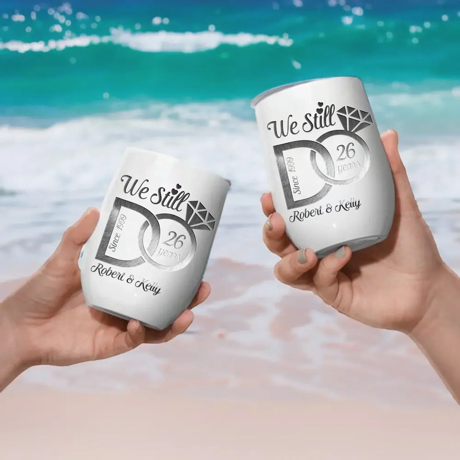 Two hands holding personalized tumblers with a beach background