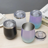 Set of gradient-colored tumblers with lids on a wooden surface.