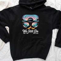 Black custom hoodie with a colorful cruise ship and sunset design, sunglasses motif, and "We Still Do" text.