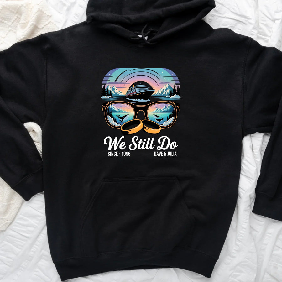 Black custom hoodie with a colorful cruise ship and sunset design, sunglasses motif, and "We Still Do" text.