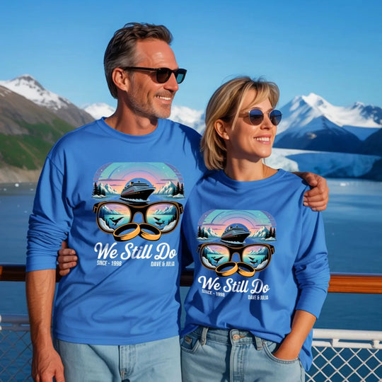 Smiling couple in matching blue custom tees with cruise and nature graphic, We Still Do text, on scenic mountain deck