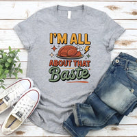 Gray t-shirt with humorous Thanksgiving graphic and text, paired with jeans and sneakers on a wooden surface.