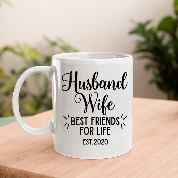 White mug with 'Husband Wife Best Friends for Life Est. 2020' text on a wooden surface with a blurred background