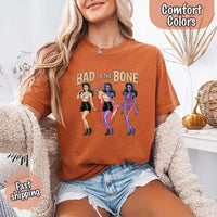May include Bad to the Bone graphic with retro pin-up girl transforming into purple skeleton artwork – vintage Halloween shirt.
