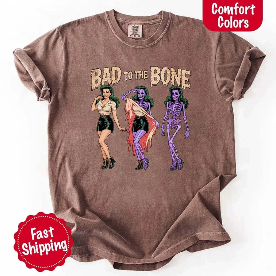 May include Bad to the Bone graphic with retro pin-up girl transforming into purple skeleton artwork – vintage Halloween shirt.