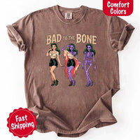 May include Bad to the Bone graphic with retro pin-up girl transforming into purple skeleton artwork – vintage Halloween shirt.