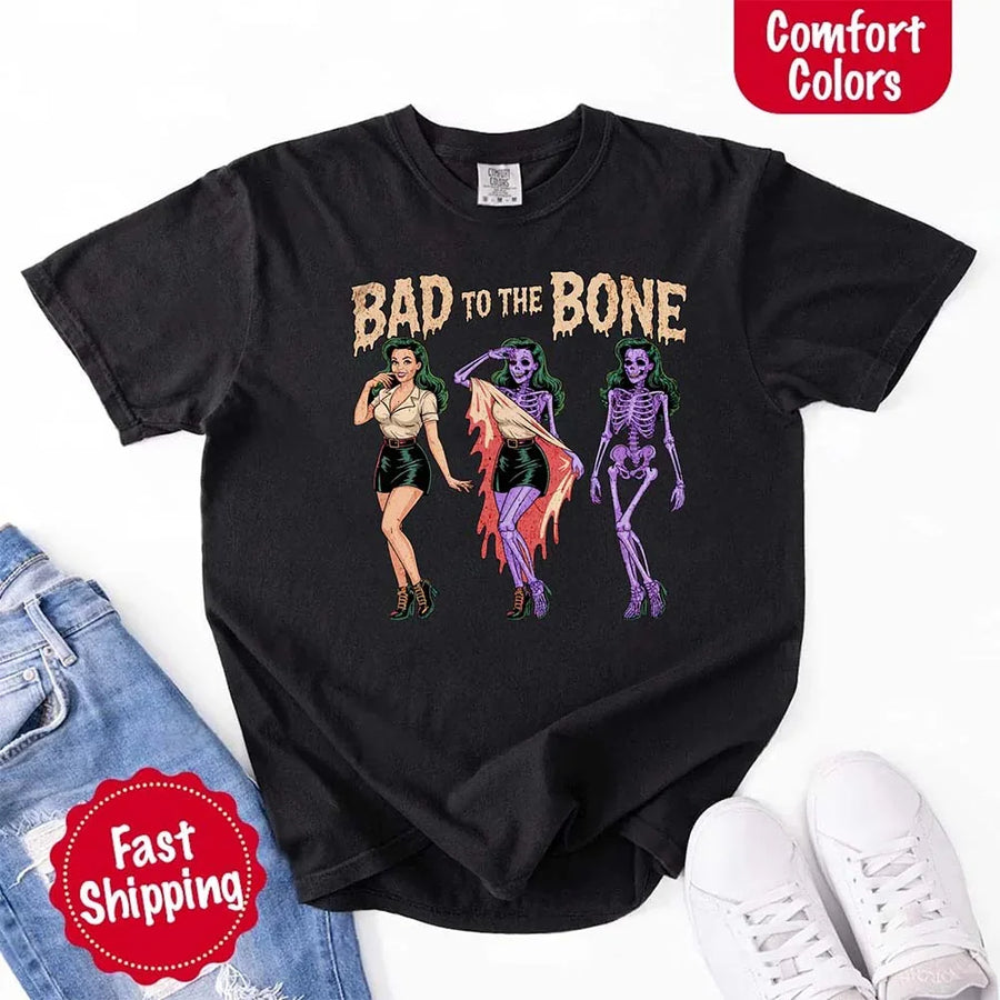 May include Bad to the Bone graphic with retro pin-up girl transforming into purple skeleton artwork – vintage Halloween shirt.