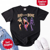 May include Bad to the Bone graphic with retro pin-up girl transforming into purple skeleton artwork – vintage Halloween shirt.