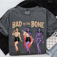 May include Bad to the Bone graphic with retro pin-up girl transforming into purple skeleton artwork – vintage Halloween shirt.