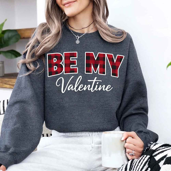 May include a buffalo plaid crewneck sweatshirt with Be My Valentine text printed on the front.