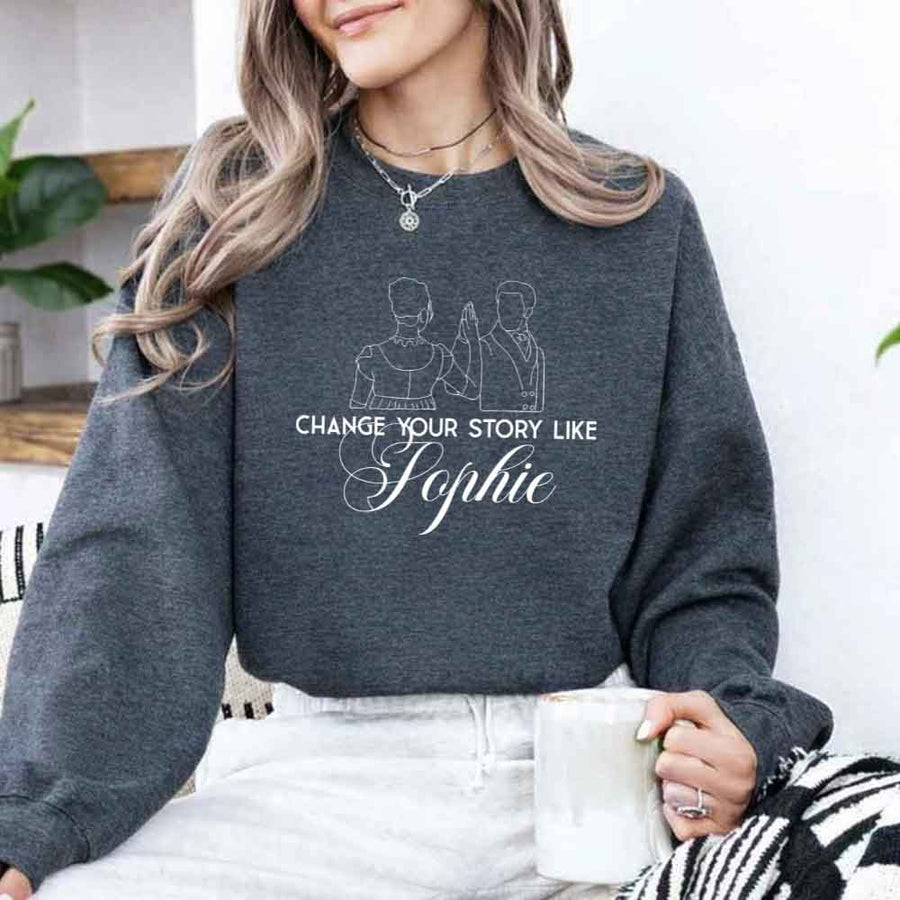 May include a person wearing a Dark Heather Change Your Story Like Sophie Crewneck Sweatshirt featuring royal inspired graphic and classic fit.