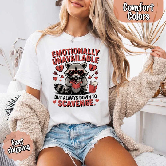 May include a red and black raccoon illustration wearing red sunglasses with the phrase “Emotionally Unavailable,” printed on a Comfort Colors tee for a bold, edgy vibe.