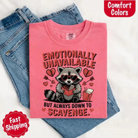 May include a red and black raccoon illustration wearing red sunglasses with the phrase “Emotionally Unavailable,” printed on a Comfort Colors tee for a bold, edgy vibe.