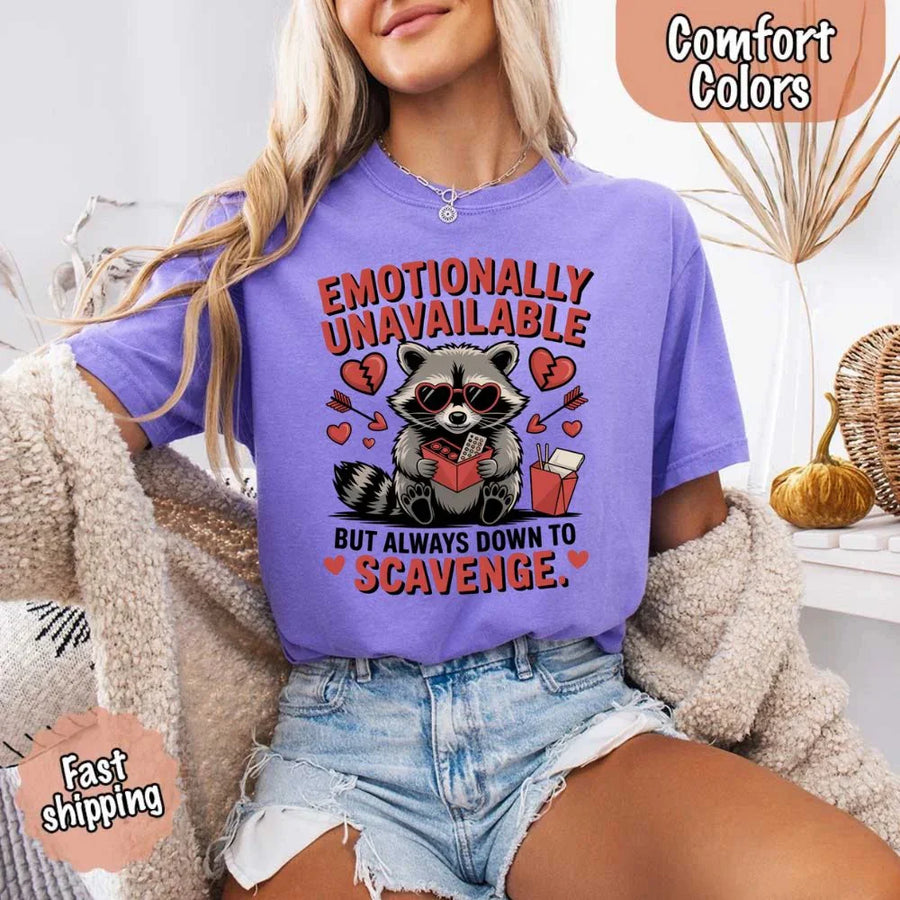May include a red and black raccoon illustration wearing red sunglasses with the phrase “Emotionally Unavailable,” printed on a Comfort Colors tee for a bold, edgy vibe.