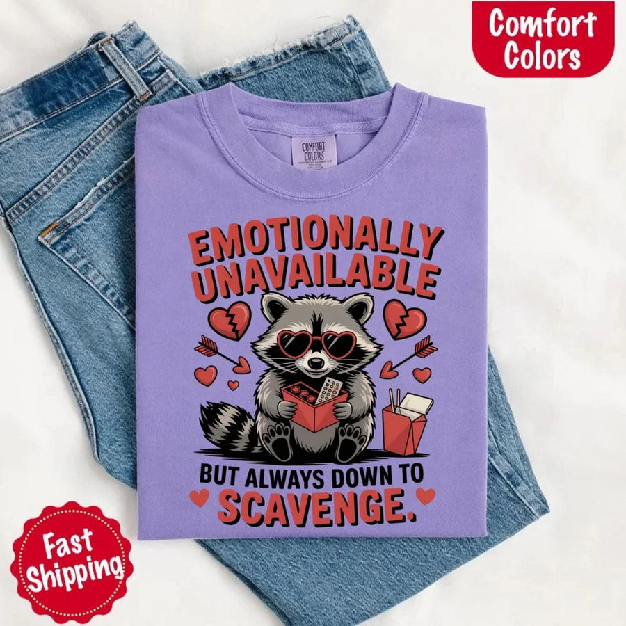 May include a red and black raccoon illustration wearing red sunglasses with the phrase “Emotionally Unavailable,” printed on a Comfort Colors tee for a bold, edgy vibe.