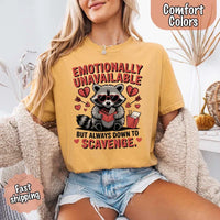 May include a red and black raccoon illustration wearing red sunglasses with the phrase “Emotionally Unavailable,” printed on a Comfort Colors tee for a bold, edgy vibe.