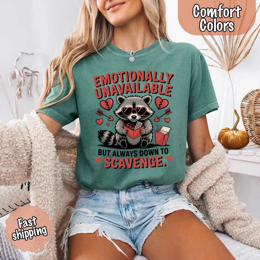 May include a red and black raccoon illustration wearing red sunglasses with the phrase “Emotionally Unavailable,” printed on a Comfort Colors tee for a bold, edgy vibe.