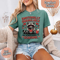 May include a red and black raccoon illustration wearing red sunglasses with the phrase “Emotionally Unavailable,” printed on a Comfort Colors tee for a bold, edgy vibe.