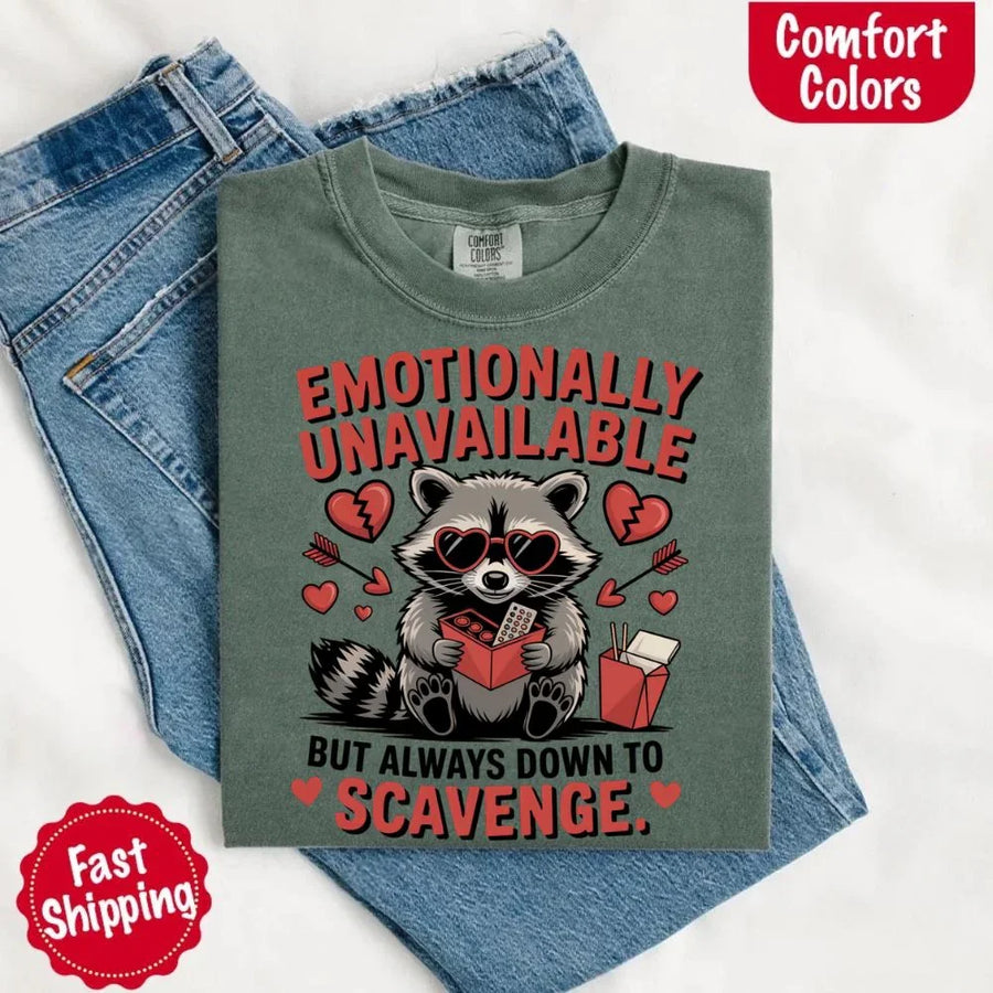 May include a red and black raccoon illustration wearing red sunglasses with the phrase “Emotionally Unavailable,” printed on a Comfort Colors tee for a bold, edgy vibe.
