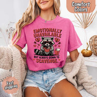 May include a red and black raccoon illustration wearing red sunglasses with the phrase “Emotionally Unavailable,” printed on a Comfort Colors tee for a bold, edgy vibe.