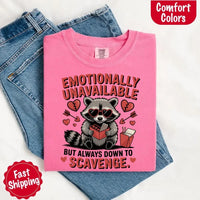 May include a red and black raccoon illustration wearing red sunglasses with the phrase “Emotionally Unavailable,” printed on a Comfort Colors tee for a bold, edgy vibe.