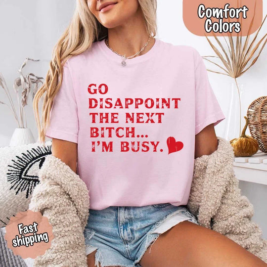 May include bold red distressed typography with the phrase “Go Disappoint The Next Bitch… I’m Busy.” alongside a red heart, expressing sass, confidence, and attitude.
