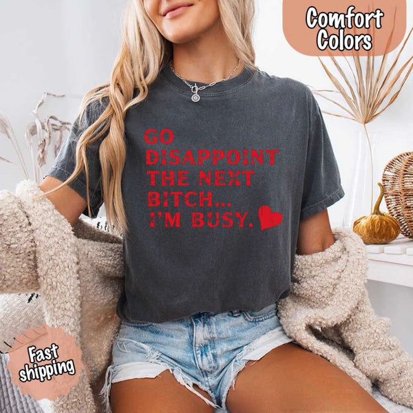 May include bold red distressed typography with the phrase “Go Disappoint The Next Bitch… I’m Busy.” alongside a red heart, expressing sass, confidence, and attitude.