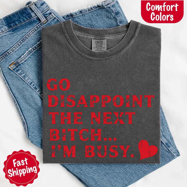 May include bold red distressed typography with the phrase “Go Disappoint The Next Bitch… I’m Busy.” alongside a red heart, expressing sass, confidence, and attitude.