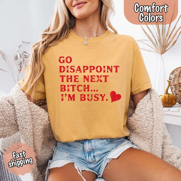 May include bold red distressed typography with the phrase “Go Disappoint The Next Bitch… I’m Busy.” alongside a red heart, expressing sass, confidence, and attitude.