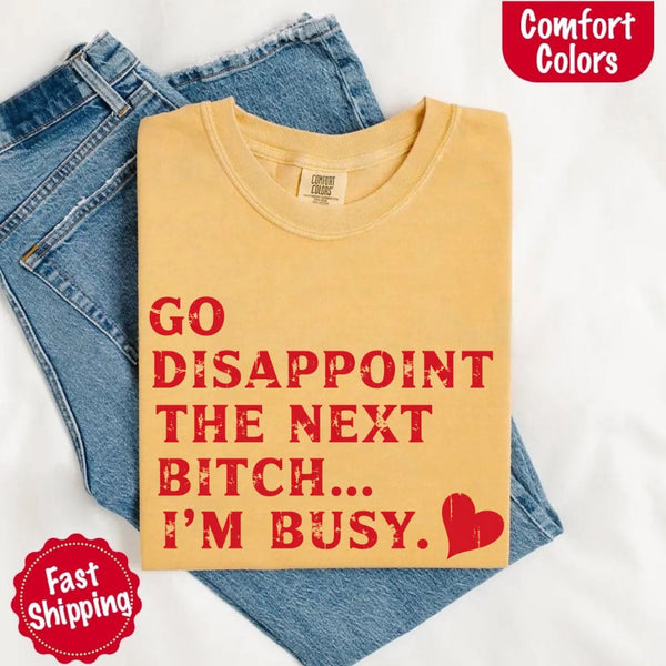 May include bold red distressed typography with the phrase “Go Disappoint The Next Bitch… I’m Busy.” alongside a red heart, expressing sass, confidence, and attitude.