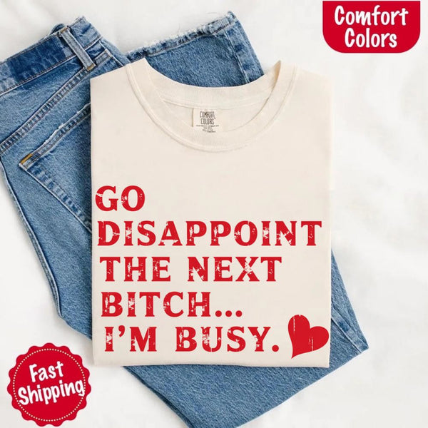 May include bold red distressed typography with the phrase “Go Disappoint The Next Bitch… I’m Busy.” alongside a red heart, expressing sass, confidence, and attitude.
