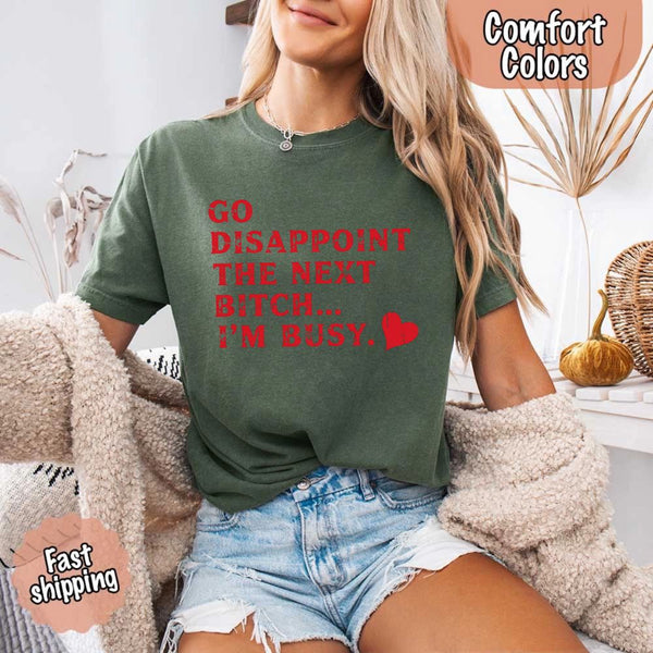 May include bold red distressed typography with the phrase “Go Disappoint The Next Bitch… I’m Busy.” alongside a red heart, expressing sass, confidence, and attitude.
