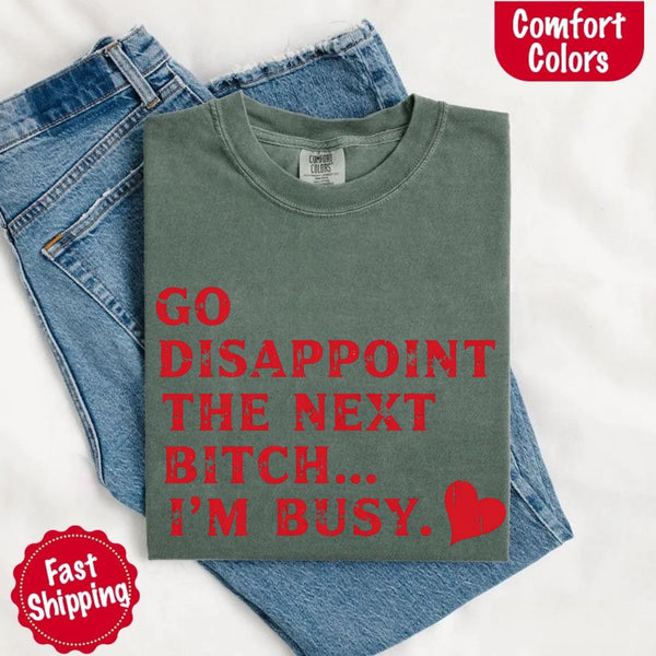May include bold red distressed typography with the phrase “Go Disappoint The Next Bitch… I’m Busy.” alongside a red heart, expressing sass, confidence, and attitude.
