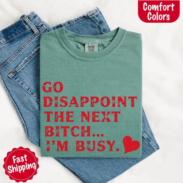May include bold red distressed typography with the phrase “Go Disappoint The Next Bitch… I’m Busy.” alongside a red heart, expressing sass, confidence, and attitude.