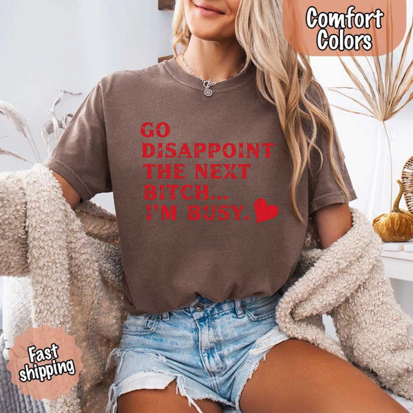 May include bold red distressed typography with the phrase “Go Disappoint The Next Bitch… I’m Busy.” alongside a red heart, expressing sass, confidence, and attitude.