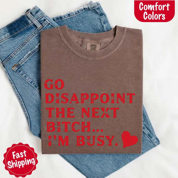 May include bold red distressed typography with the phrase “Go Disappoint The Next Bitch… I’m Busy.” alongside a red heart, expressing sass, confidence, and attitude.