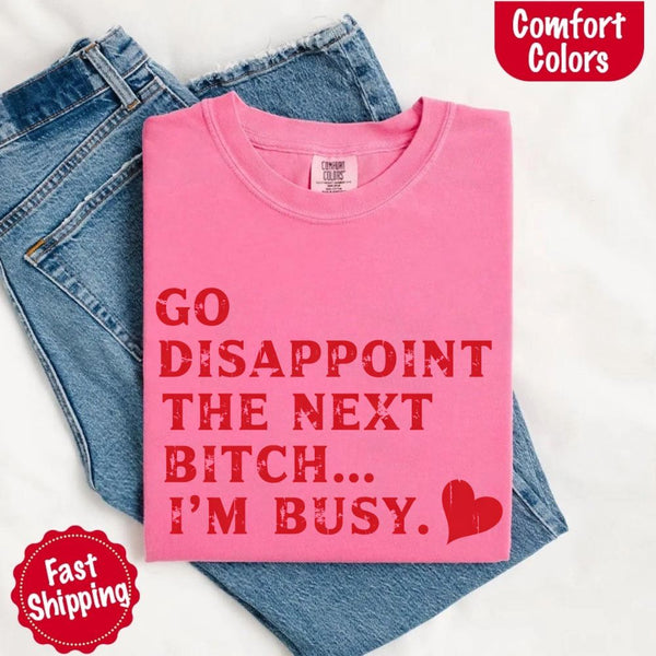 May include bold red distressed typography with the phrase “Go Disappoint The Next Bitch… I’m Busy.” alongside a red heart, expressing sass, confidence, and attitude.